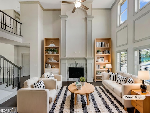 living room with a high end fireplace, stairs, a towering ceiling, and ornamental molding