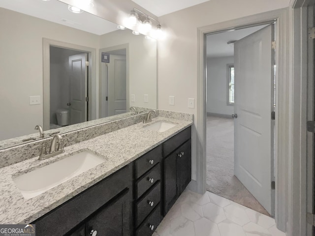 bathroom featuring double vanity, toilet, and a sink