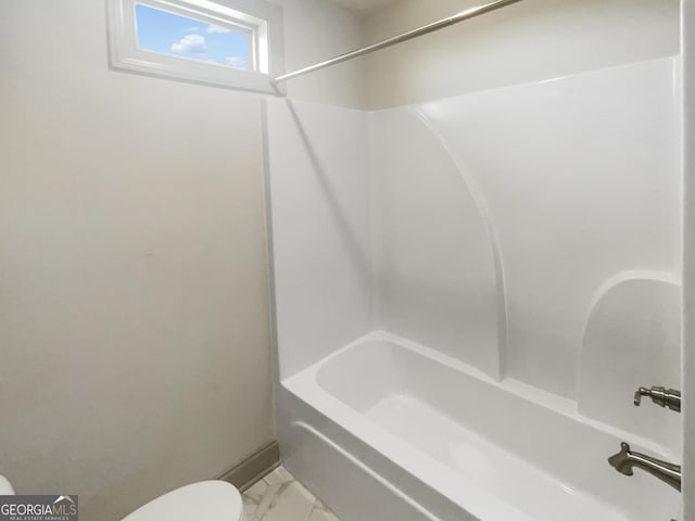 bathroom featuring marble finish floor, toilet, and shower / bathtub combination