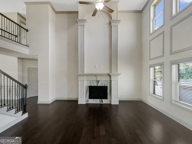 unfurnished living room featuring baseboards, stairway, ornamental molding, a premium fireplace, and dark wood-style floors