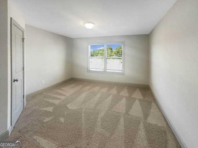 unfurnished room featuring baseboards and light carpet