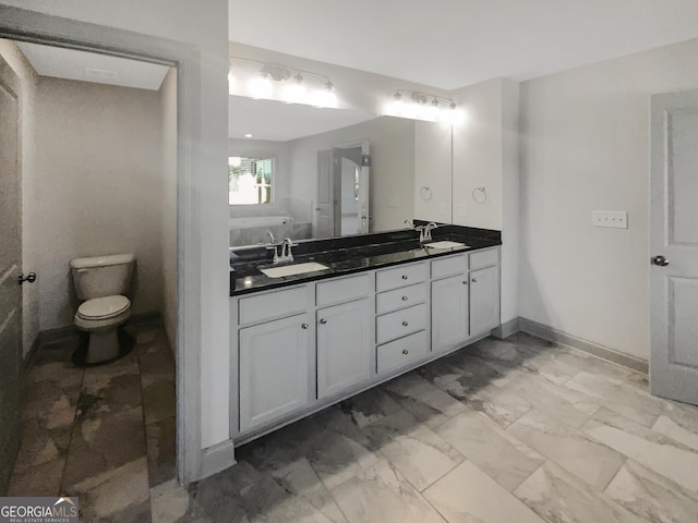 full bath with double vanity, marble finish floor, toilet, and a sink