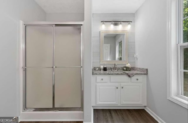 bathroom with vanity, wood finished floors, a stall shower, and baseboards