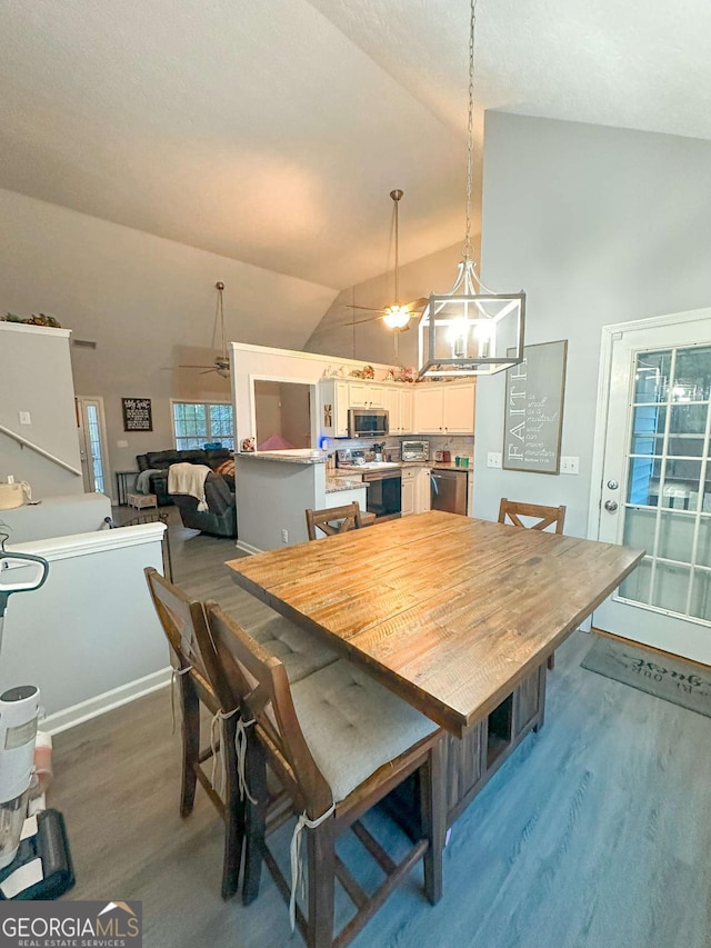 dining space with a chandelier, high vaulted ceiling, and wood finished floors