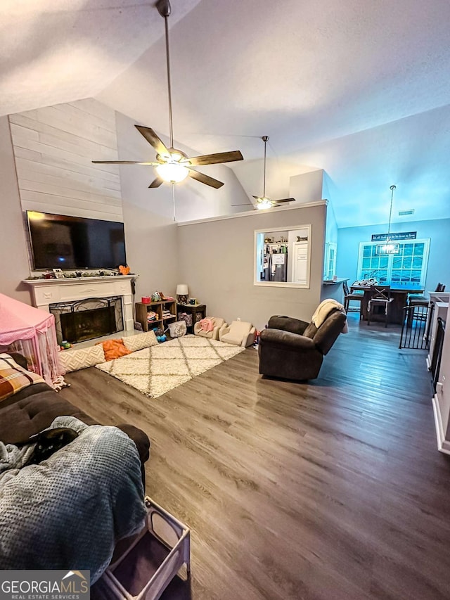 living area featuring vaulted ceiling, wood finished floors, and a ceiling fan