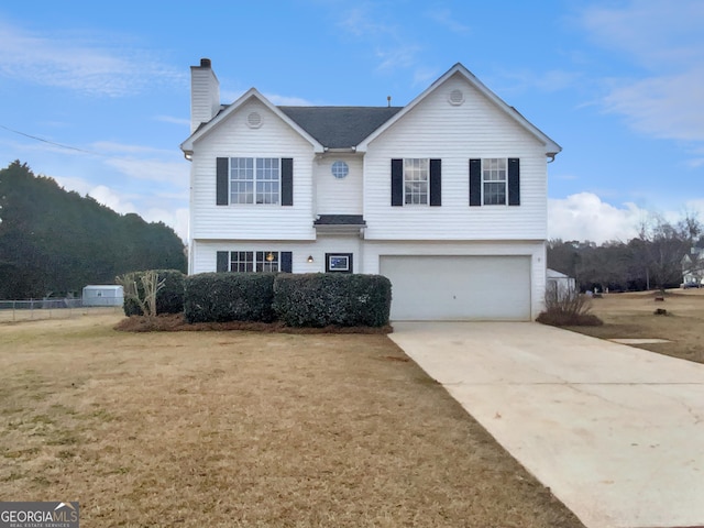 traditional-style house with a front yard, an attached garage, a chimney, and driveway