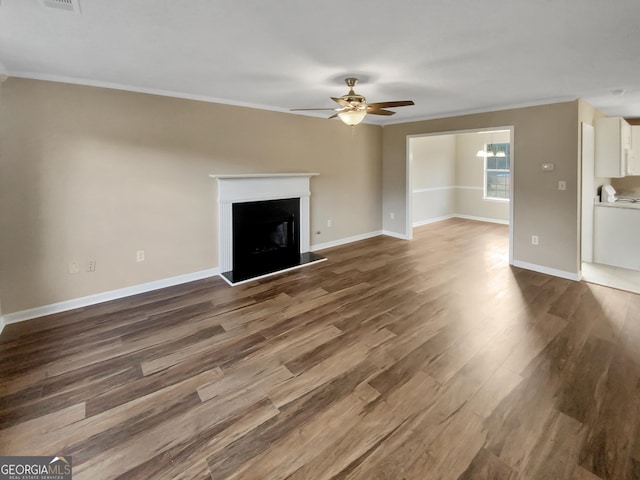 unfurnished living room with a fireplace with raised hearth, wood finished floors, crown molding, baseboards, and ceiling fan