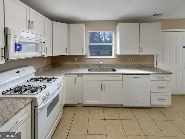 kitchen featuring visible vents, a sink, white appliances, white cabinets, and light tile patterned floors