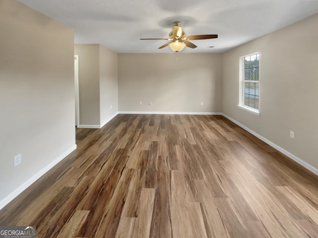 empty room with a ceiling fan, baseboards, and dark wood-style flooring