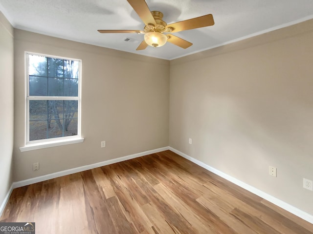 unfurnished room with visible vents, wood finished floors, baseboards, and ceiling fan