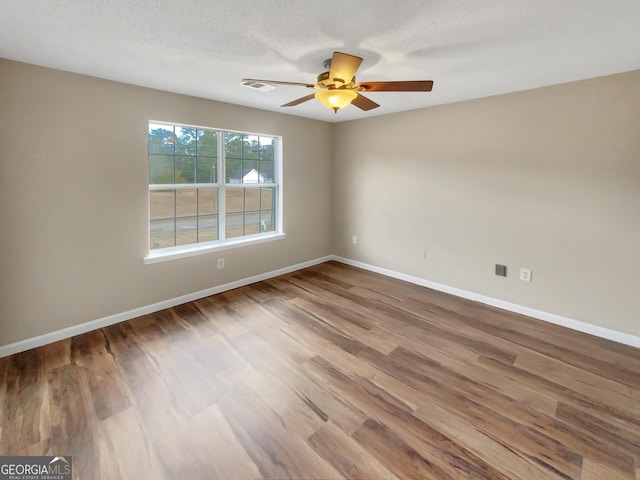 empty room featuring visible vents, baseboards, wood finished floors, and a ceiling fan