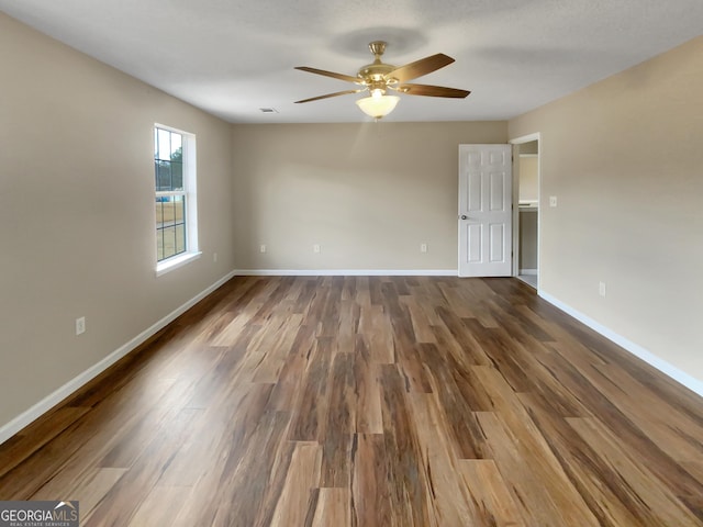 spare room with baseboards, dark wood-type flooring, and a ceiling fan