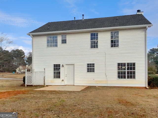 rear view of property with a patio, a lawn, and a chimney