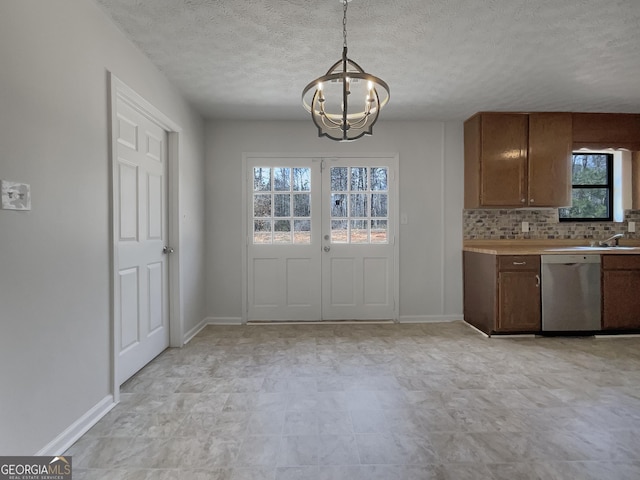 kitchen featuring a notable chandelier, stainless steel dishwasher, french doors, decorative backsplash, and baseboards