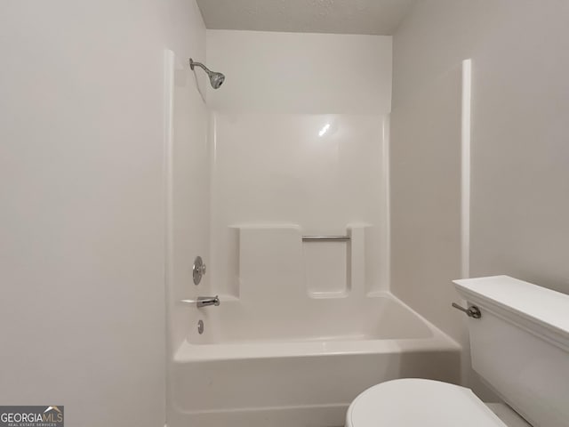 full bathroom featuring bathtub / shower combination, toilet, and a textured ceiling