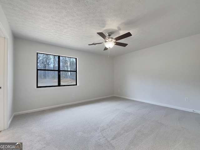 empty room with light colored carpet, a textured ceiling, baseboards, and ceiling fan