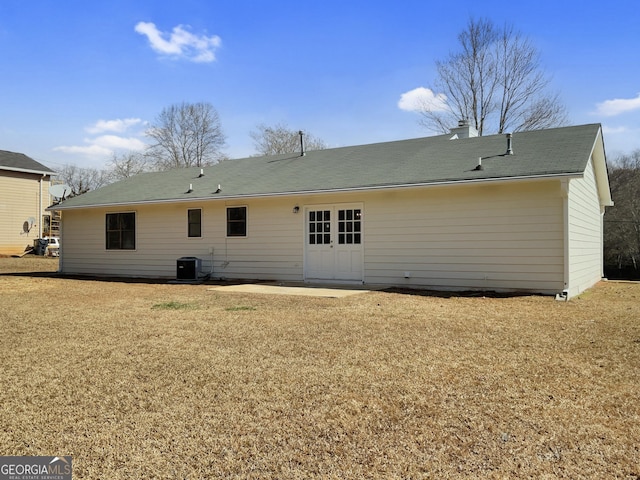 back of house featuring a lawn, central AC, and a chimney