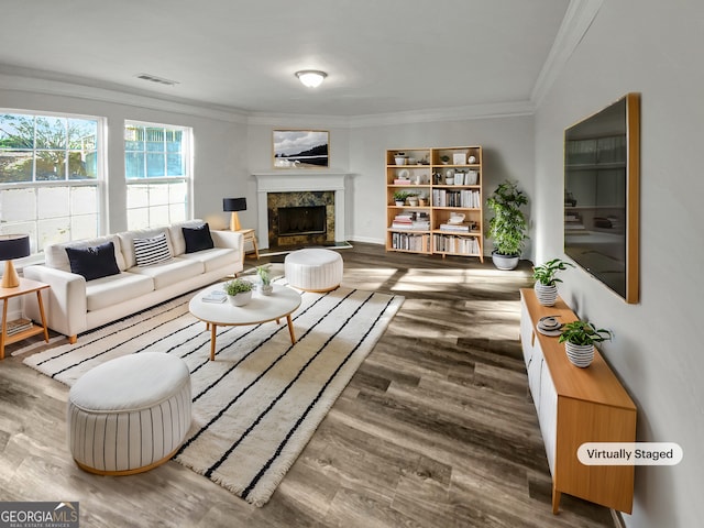 living area featuring visible vents, wood finished floors, ornamental molding, and a fireplace