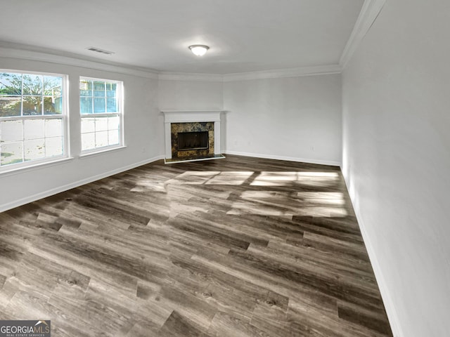 unfurnished living room featuring visible vents, dark wood-style floors, crown molding, a premium fireplace, and baseboards