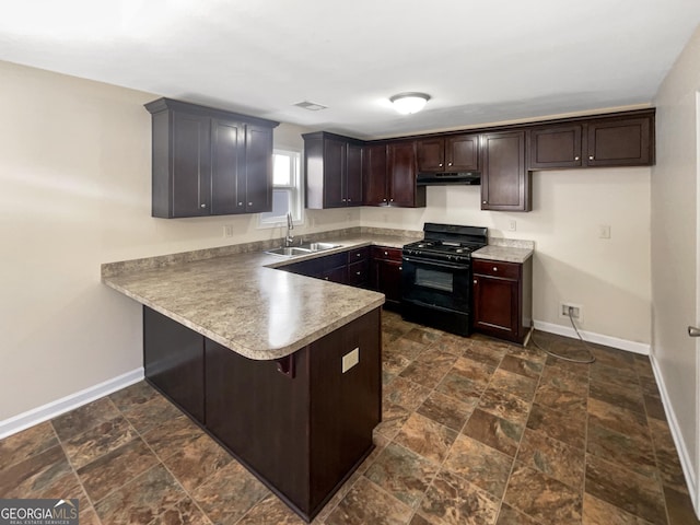 kitchen with a sink, under cabinet range hood, black gas range oven, a peninsula, and baseboards