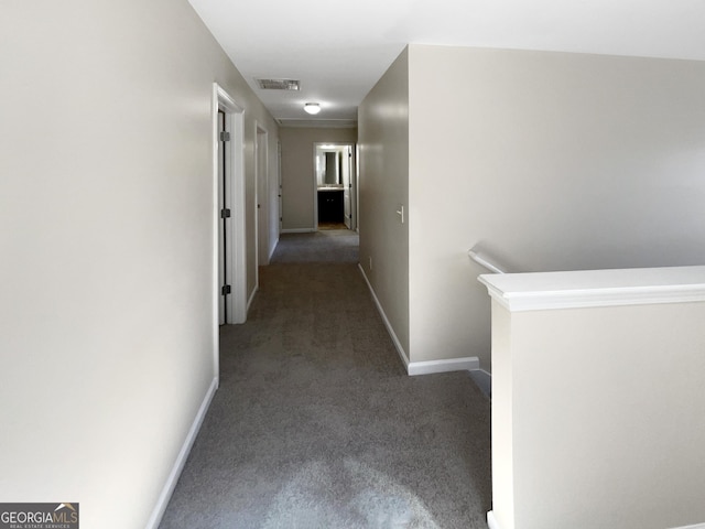 hallway featuring an upstairs landing, visible vents, baseboards, and carpet