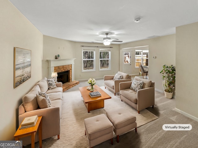 living room with a brick fireplace, a ceiling fan, baseboards, and carpet floors