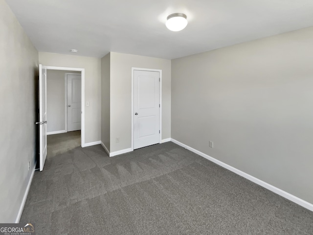 unfurnished bedroom featuring baseboards and dark carpet