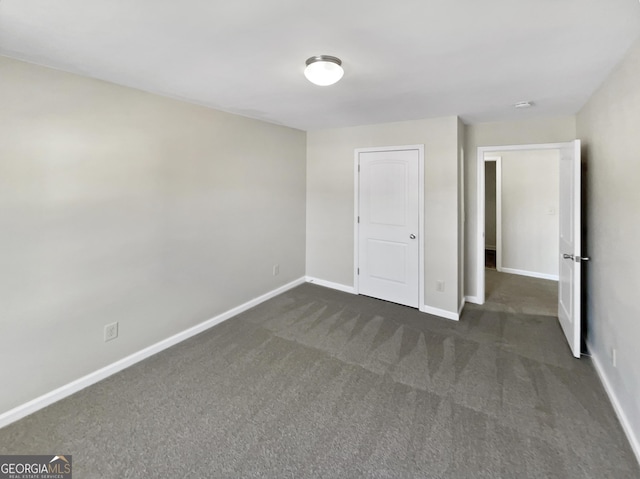 interior space featuring dark colored carpet and baseboards