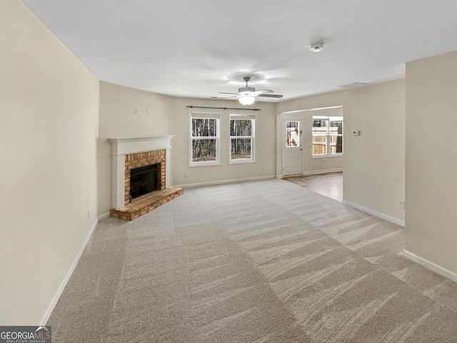 unfurnished living room featuring baseboards, carpet, a brick fireplace, and ceiling fan