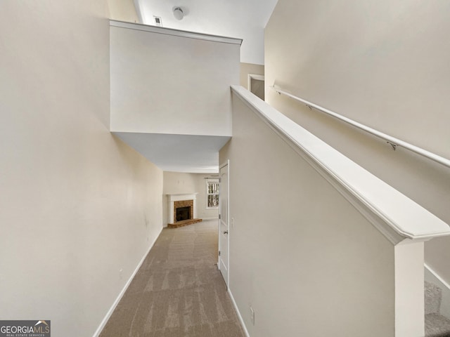 hallway featuring baseboards, stairs, and carpet