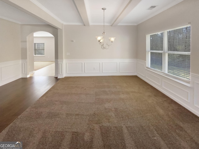 unfurnished room with beam ceiling, plenty of natural light, and carpet floors