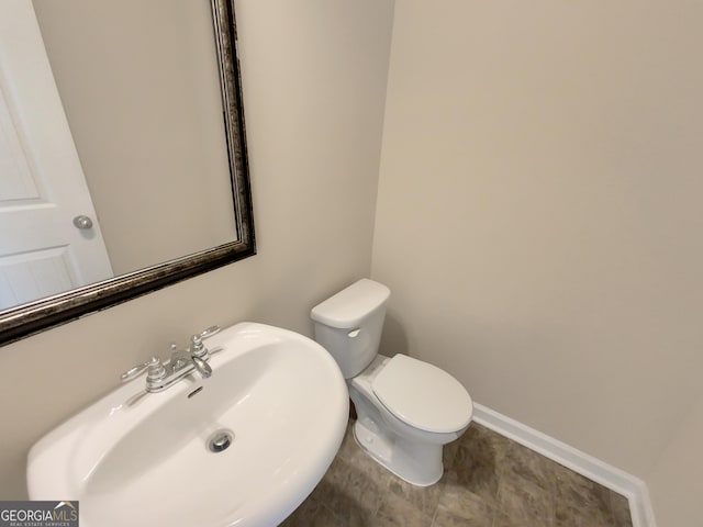 half bathroom with a sink, baseboards, and toilet