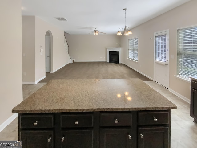 1181 Paramount Dr, Mcdonough, GA 30253 - kitchen featuring a ceiling fan, a kitchen island, dark cabinets, a fireplace, and plenty of natural light