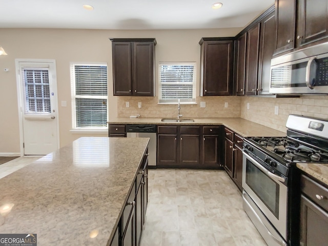 kitchen featuring a sink, dark brown cabinetry, light stone countertops, and stainless steel appliances