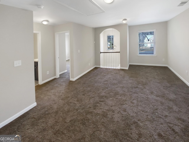 spare room featuring visible vents, attic access, baseboards, and dark colored carpet