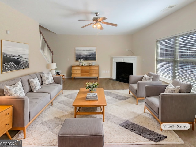 living area featuring visible vents, a fireplace with flush hearth, baseboards, and ceiling fan