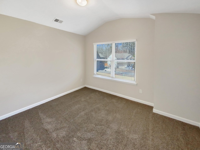 empty room featuring visible vents, baseboards, dark colored carpet, and vaulted ceiling