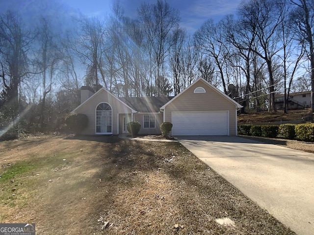 view of front facade with concrete driveway, a garage, and a chimney