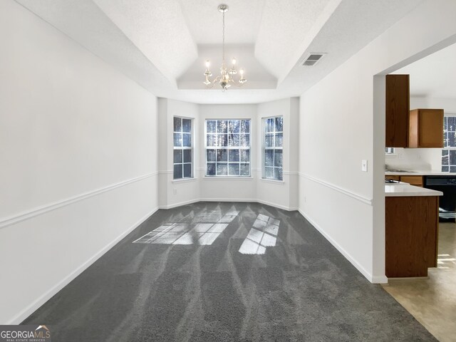 unfurnished dining area with visible vents, baseboards, a chandelier, a tray ceiling, and dark colored carpet