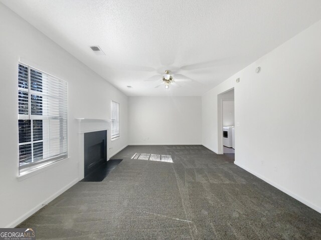 unfurnished living room featuring visible vents, ceiling fan, a fireplace with flush hearth, carpet floors, and a textured ceiling