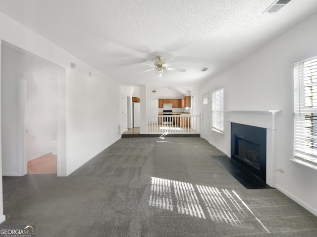 unfurnished living room featuring a wealth of natural light, visible vents, a fireplace with flush hearth, and carpet