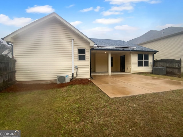 rear view of property with a patio, a yard, fence, and central AC