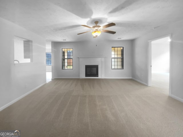 unfurnished living room featuring baseboards, plenty of natural light, light carpet, and a fireplace