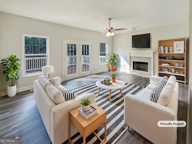 living room with french doors, a fireplace, baseboards, and wood finished floors