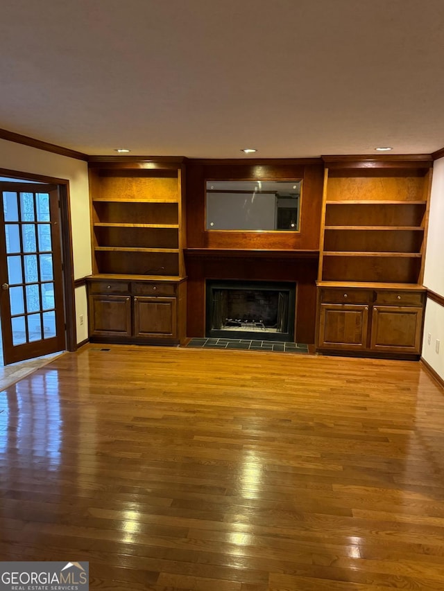 unfurnished living room featuring baseboards, ornamental molding, recessed lighting, a fireplace, and wood finished floors