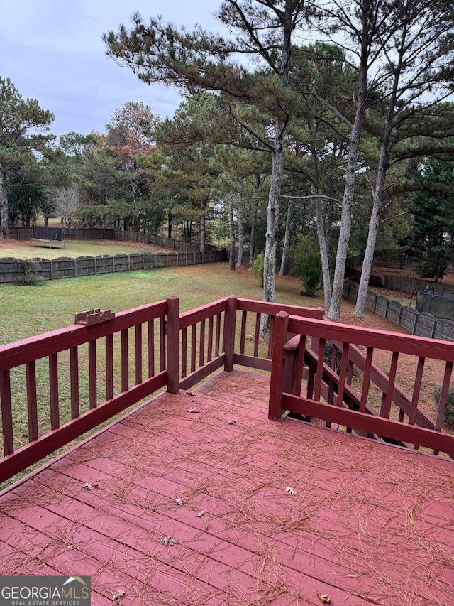 wooden terrace featuring a lawn and fence