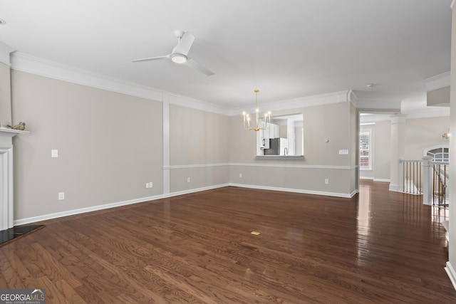 unfurnished living room with ornamental molding, a fireplace with raised hearth, dark wood-style flooring, and ceiling fan with notable chandelier