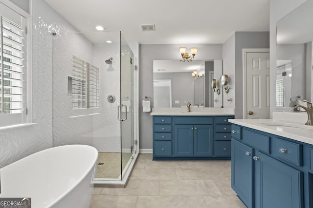 bathroom featuring a shower stall, a freestanding tub, two vanities, and a sink