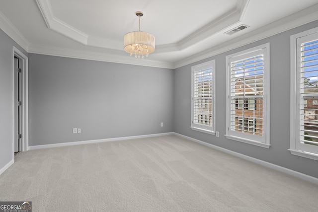 spare room with a tray ceiling, light colored carpet, visible vents, and baseboards