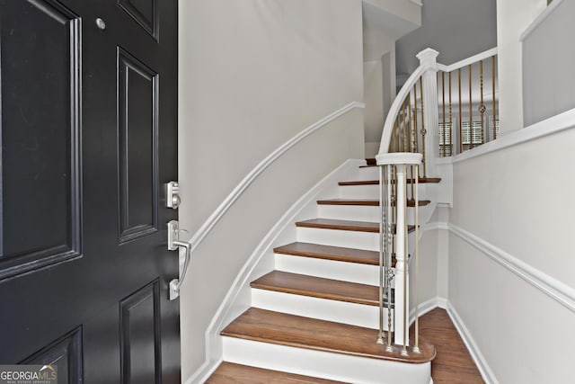 foyer with stairs, wood finished floors, and baseboards